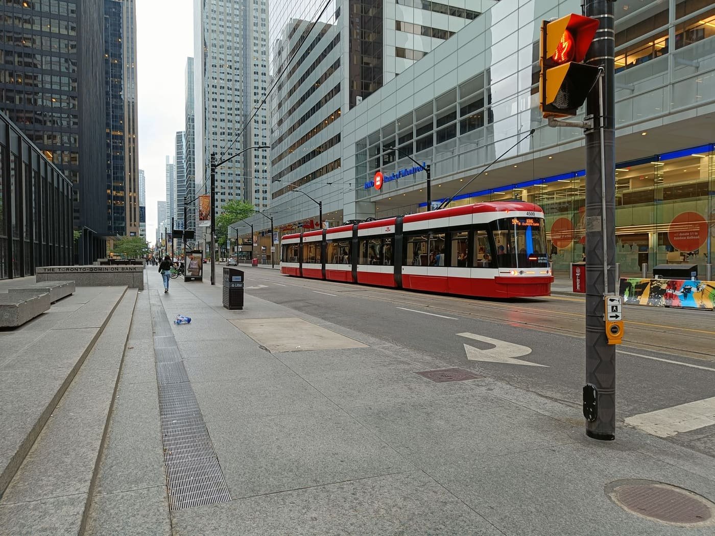 A red TTC streetcar passing office towers in Toronto's Financial District