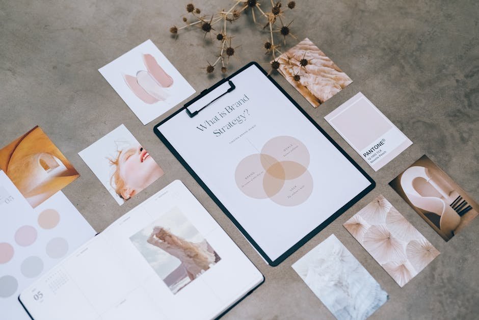 Designer arranging brand identity materials including logo sketches, colour swatches, and typography samples on a studio desk