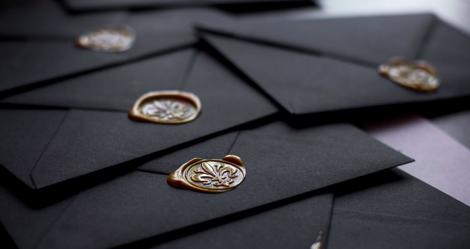 Black envelopes closed with gold wax seals