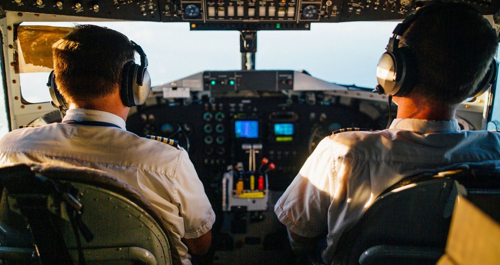 Two pilots side by side in an airliner cockpit, hands on the controls