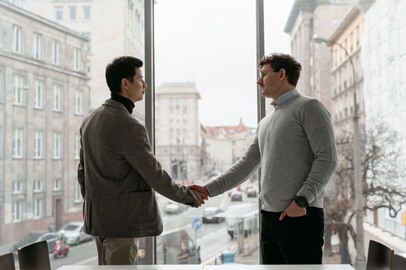 Two people shaking hands in an office with the Toronto skyline through the window — agreeing terms with a local web design agency