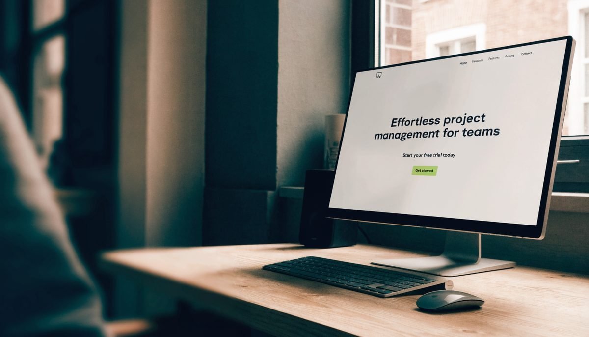 Modern computer monitor displaying a clean SaaS landing page with a prominent call-to-action button highlighted, on a minimalist Toronto agency desk