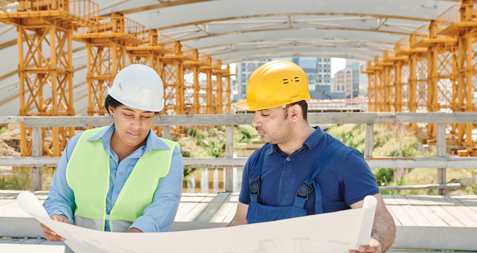 An architect and a builder reviewing blueprints together on a construction site