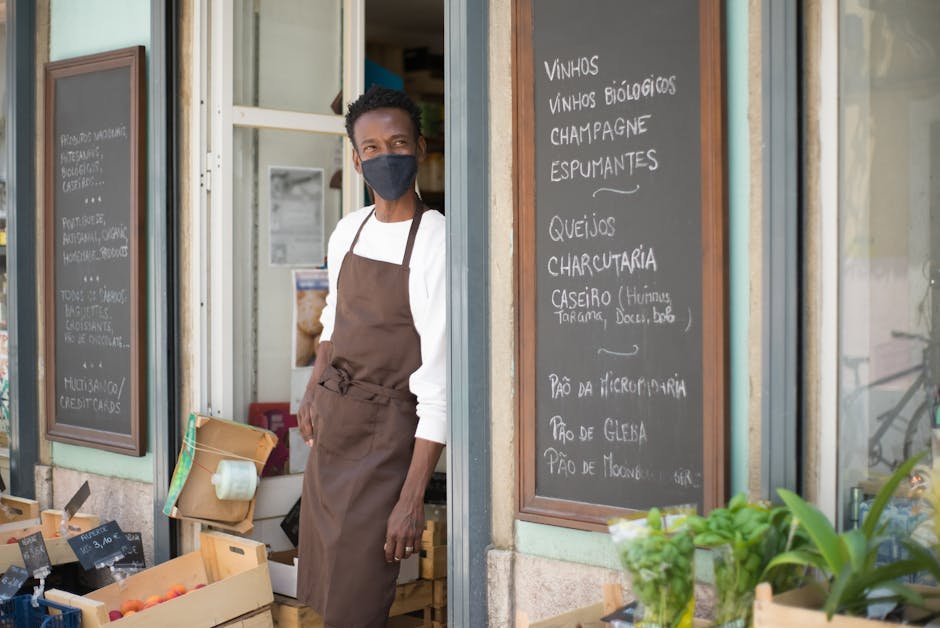 Small business owner working on laptop in boutique storefront with products in background