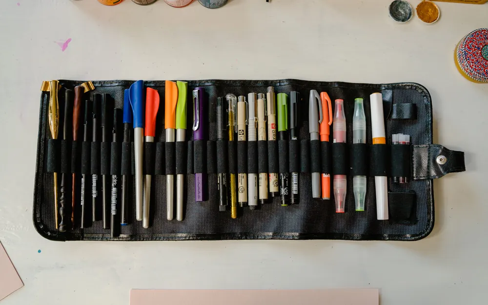 A roll-up case of drawing pens and markers opened out flat