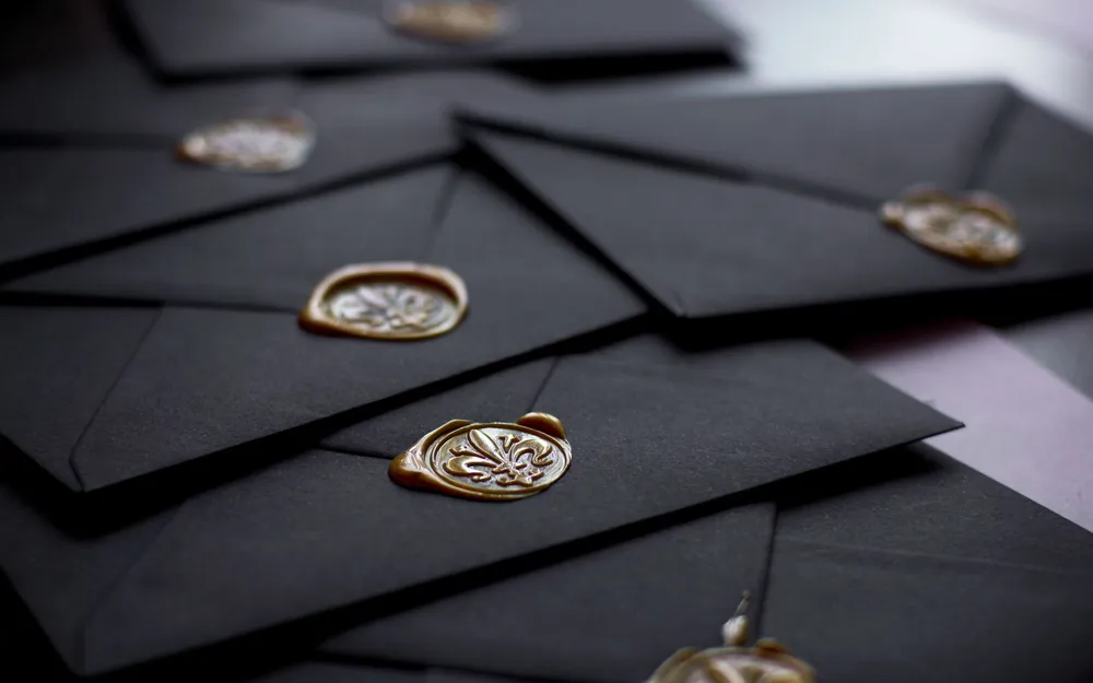 Black envelopes closed with gold wax seals