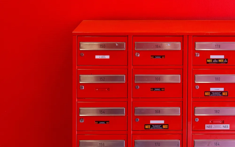 A grid of red post office boxes set into a wall