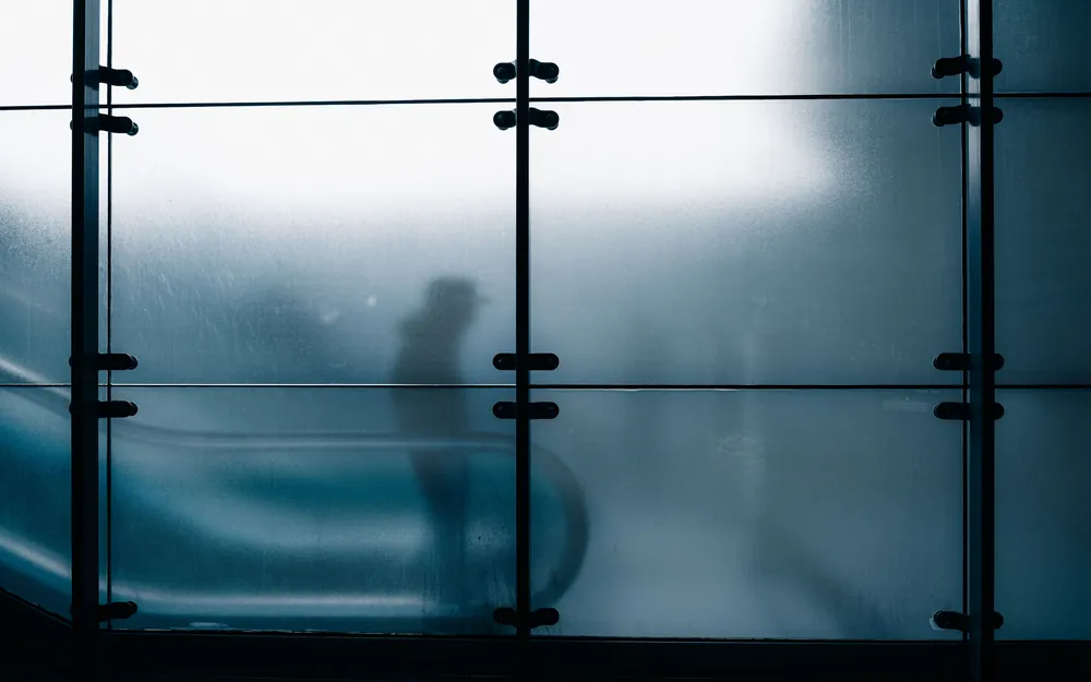 An indistinct silhouette seen through a pane of frosted glass