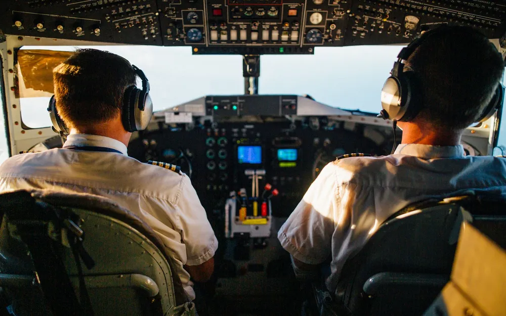 Two pilots side by side in an airliner cockpit, hands on the controls