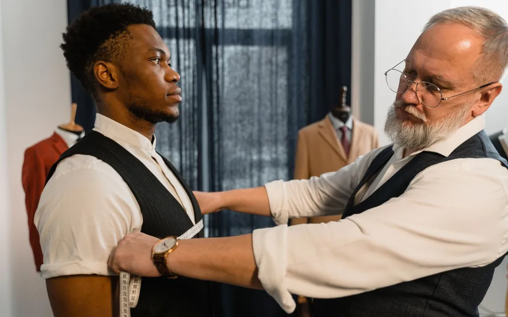 A tailor measuring a client for a bespoke suit in a tailoring atelier