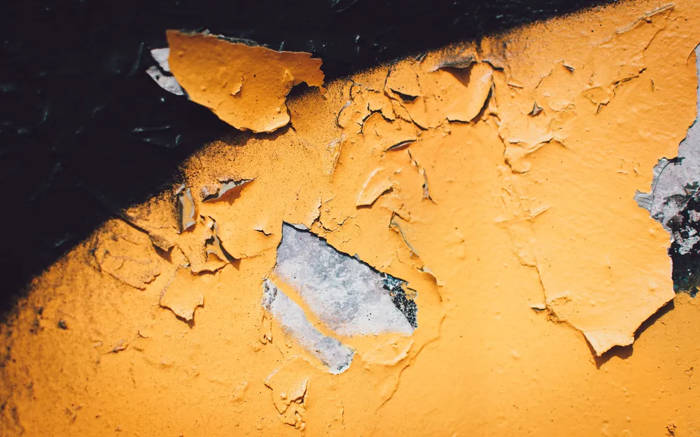 Cracked orange paint flaking away from a weathered surface