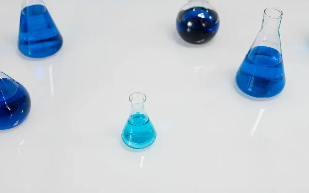Laboratory flasks holding blue liquid on a white surface