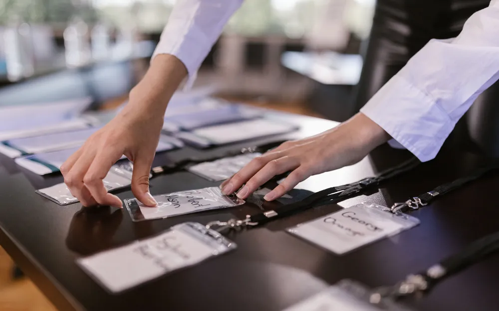 Hands arranging printed name badges on a conference registration table