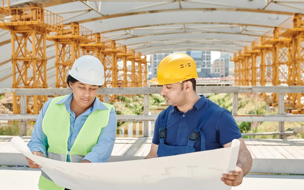 An architect and a builder reviewing blueprints together on a construction site