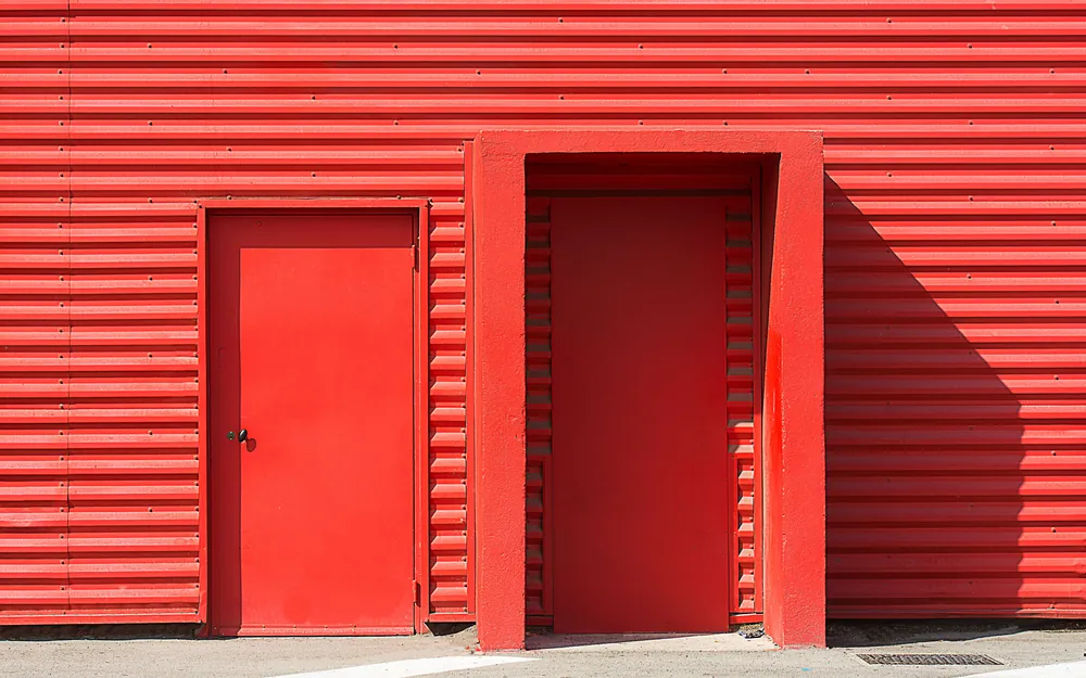 Two doors set into a bright red corrugated metal wall