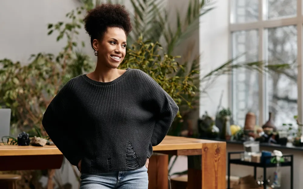 A business owner standing in a bright, plant-filled studio space