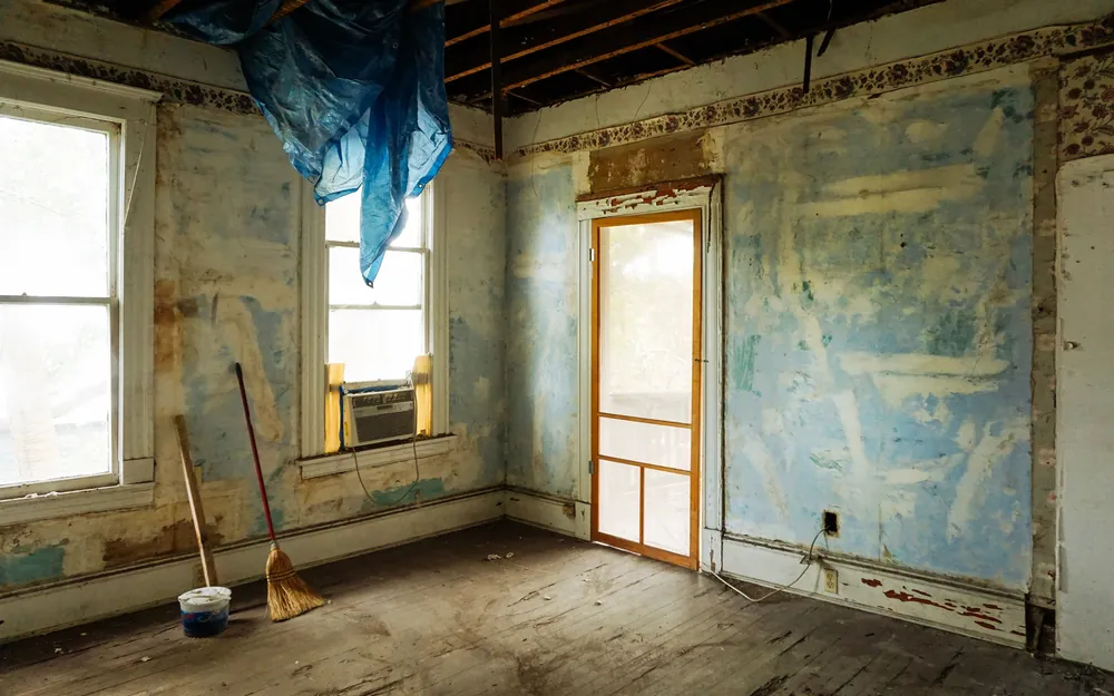 An empty room stripped back to bare plaster and studs mid-renovation