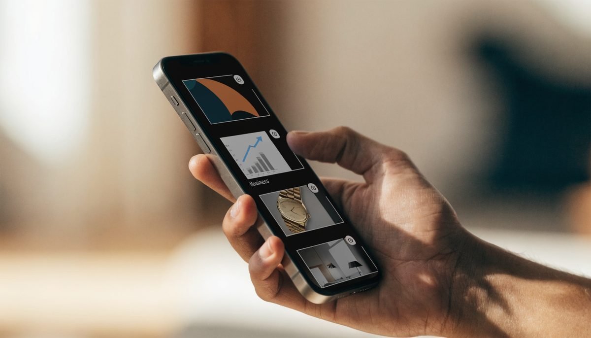 Close-up of a hand holding a smartphone displaying a vertical short-form social video feed with business content thumbnails